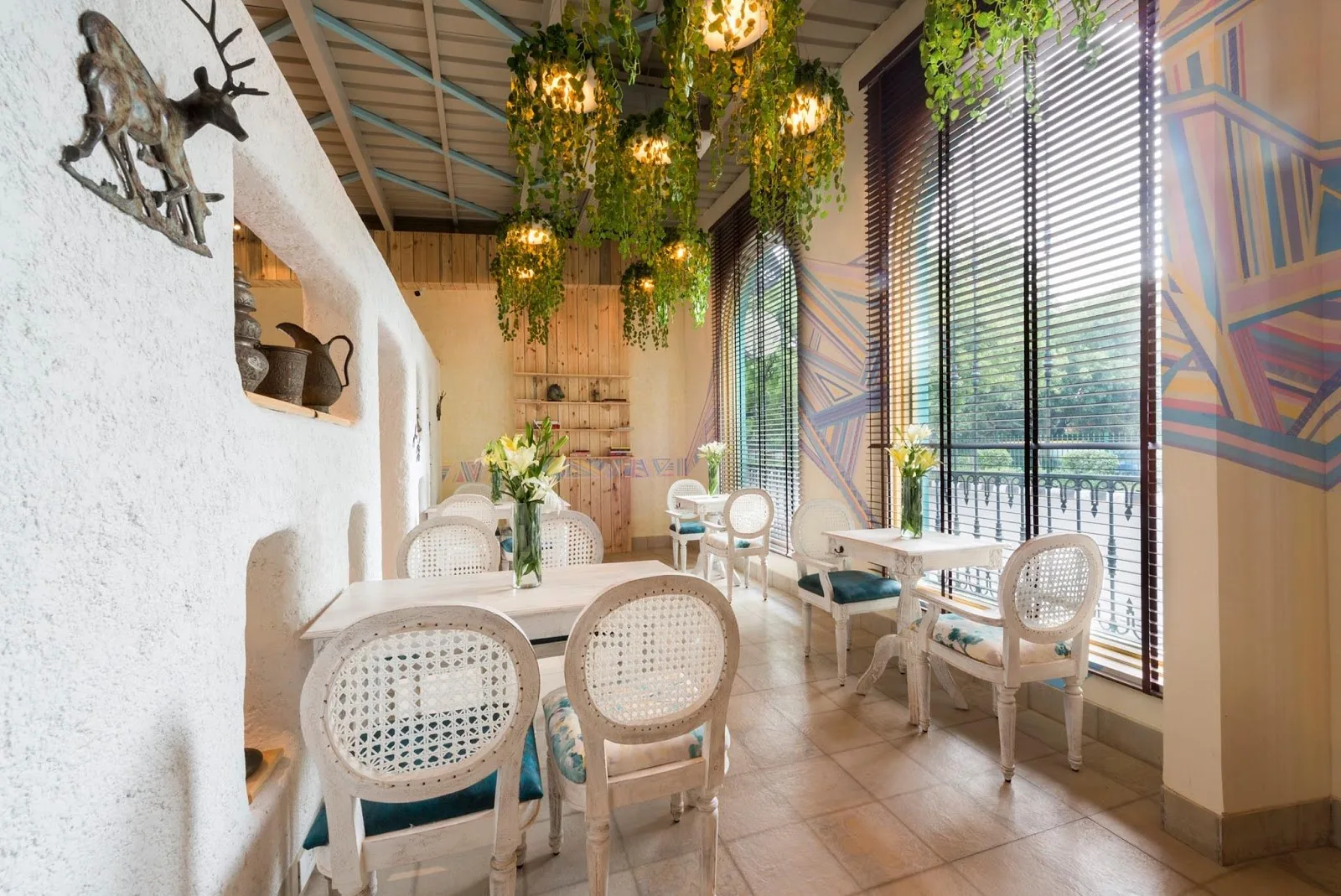 Café Tesu’s sunlit dining room with white arches and hanging greenery